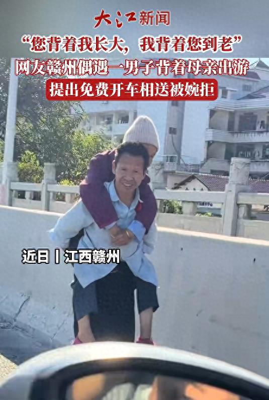 男子背着母亲在路边行走,热心司机询问其原因男子笑着说“带妈妈去玩”,司机邀请其搭车被婉拒;网友:孝道在此刻具象化